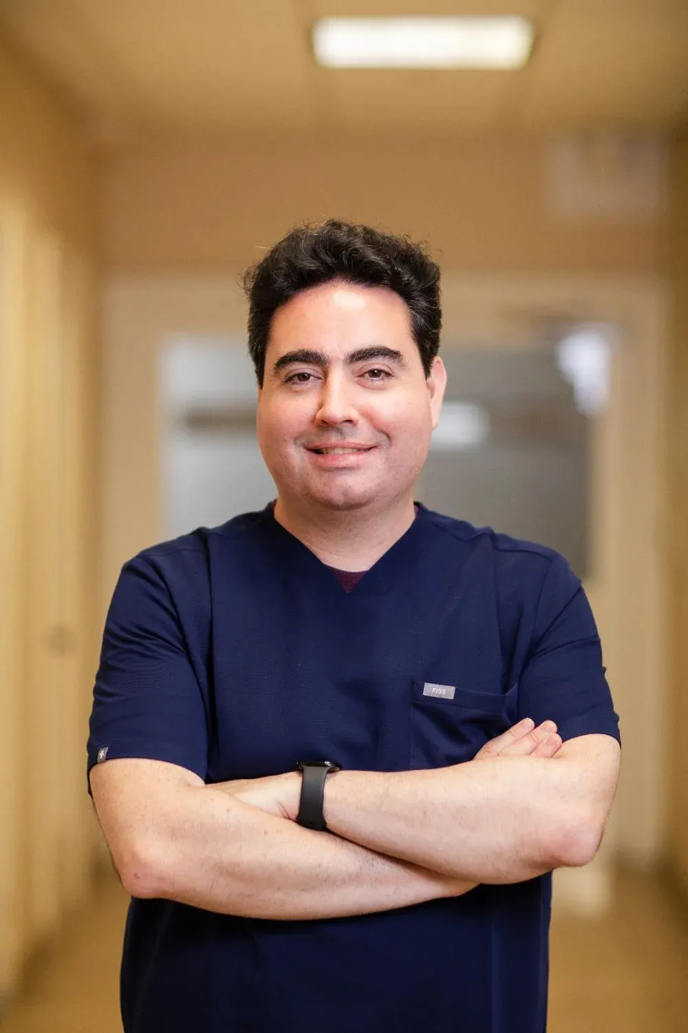 Dr. Alexander Black, DDS, dentist at Creative Dentistry of Brooklyn Heights, standing with arms crossed in the office hallway