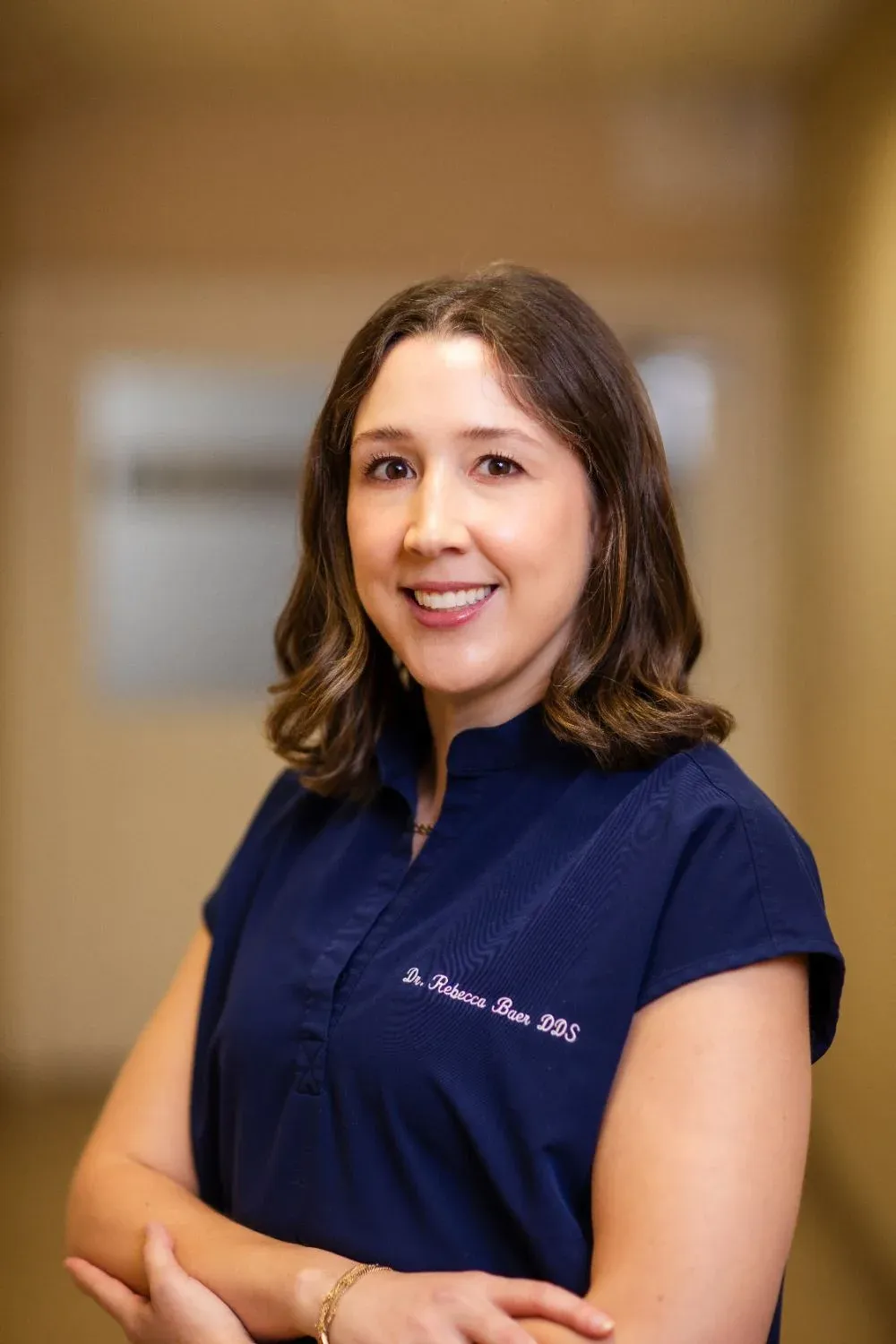 Dr. Rebecca Baer, DDS, dentist at Creative Dentistry of Brooklyn Heights, smiling with arms crossed in the office hallway