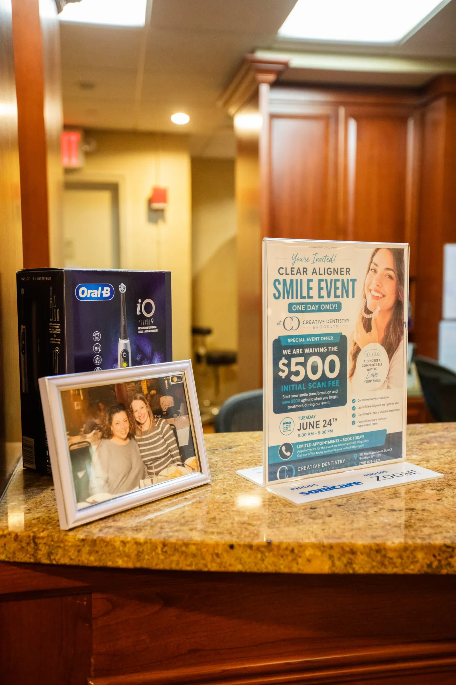 Front desk display at Creative Dentistry of Brooklyn Heights with Clear Aligner Smile Event flyer and Oral-B iO toothbrush
