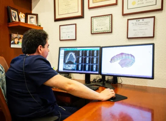 Dentist reviewing digital X-rays and a 3D scan on dual monitors in Dr. Matthew Bellafiore's office at Creative Dentistry of Brooklyn Heights