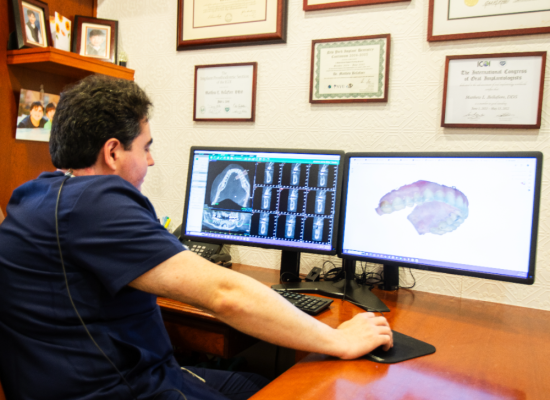 Dentist reviewing digital X-rays and a 3D scan on dual monitors in Dr. Matthew Bellafiore's office at Creative Dentistry of Brooklyn Heights