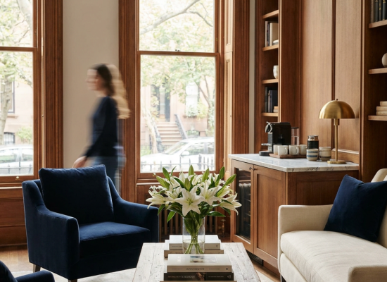 Cozy living room-style waiting area with navy armchairs, a bookshelf, and arched windows